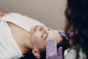 Young woman getting face massage with cosmetics cream in beauty spa. - Face and Body Institute