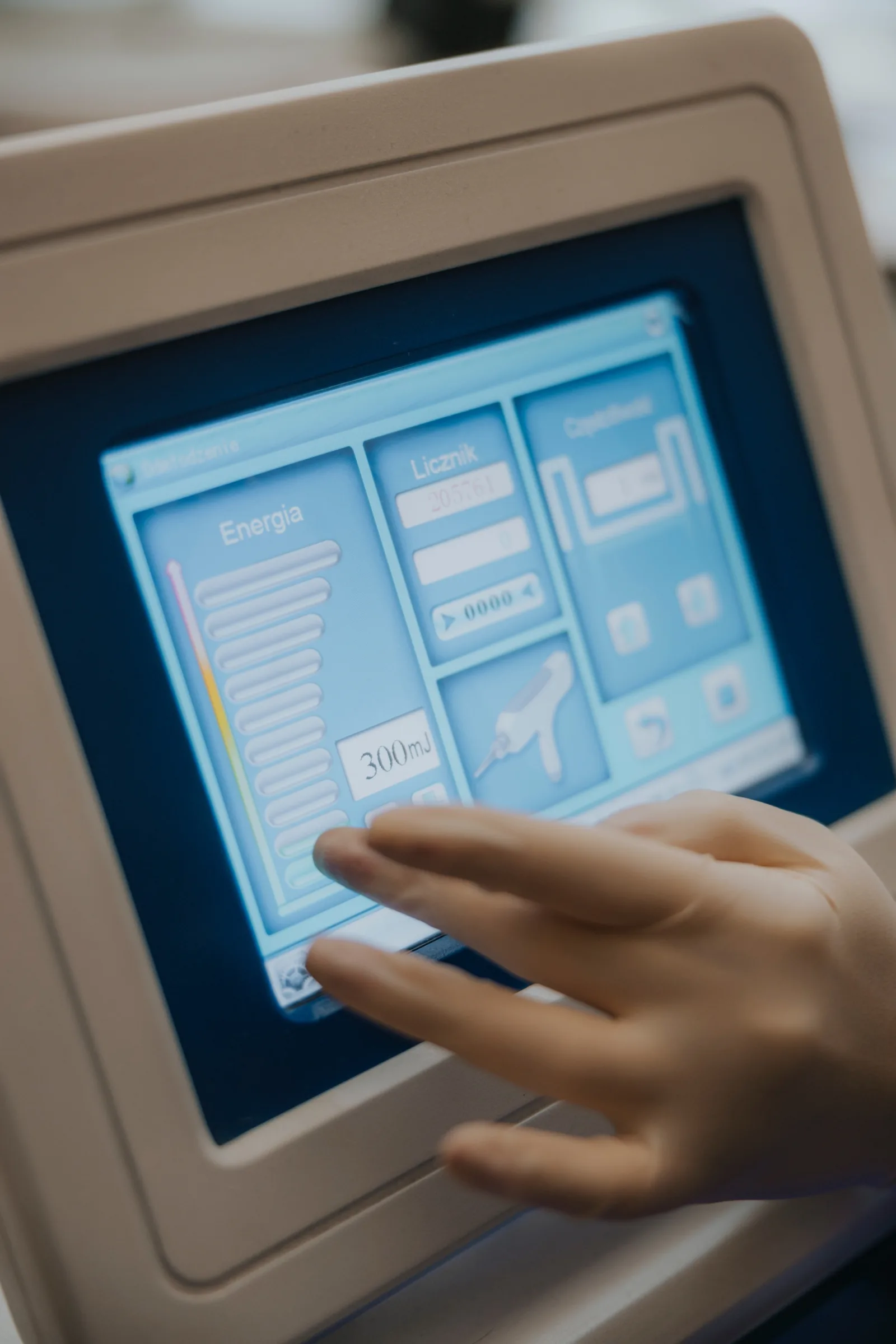 Gloved hand setting the energy level on the laser touchscreen before hair removal