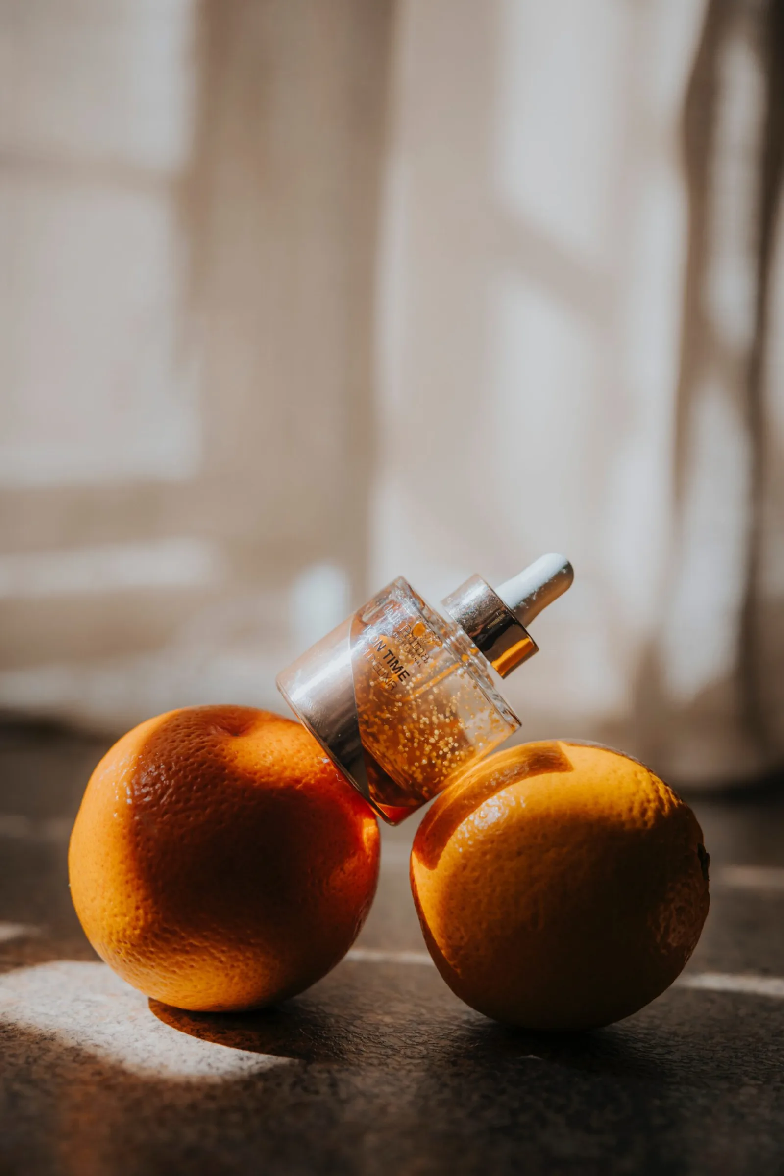 Serum bottle with a pipette resting against oranges, antioxidant vitamin C care