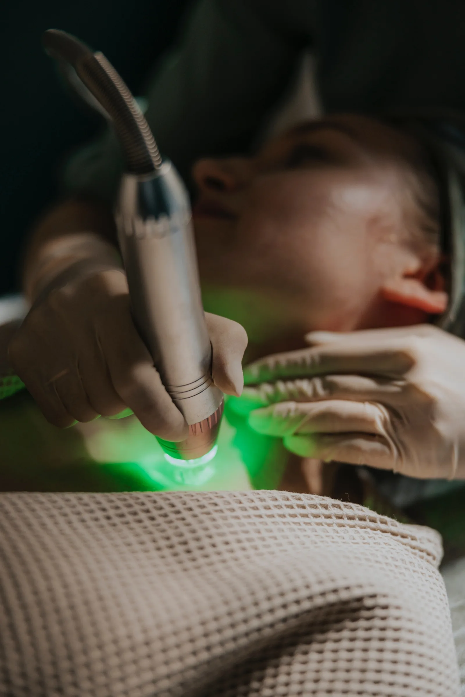Głowica emitująca zielone światło prowadzona po twarzy pacjentki podczas zabiegu BIOREGEN 360